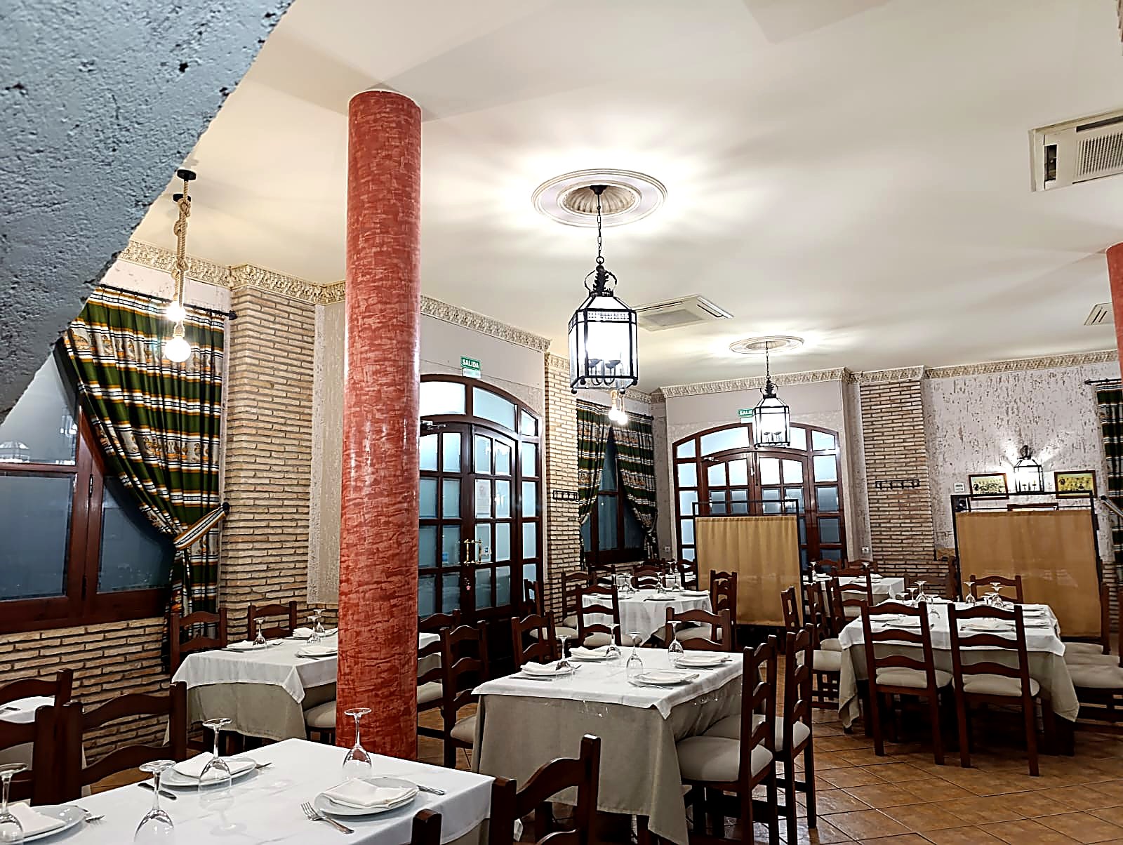 Salón grande del mesón con mesas vestidas y faroles